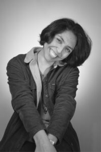 Johanna Romo for LEAD. Black and white photograph of Johanna smiling and leaning to the right while wearing a denim jacket