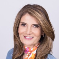 Mahtab Jafari headshot photo with a black background while wearing a colorful shift and light blue blazer